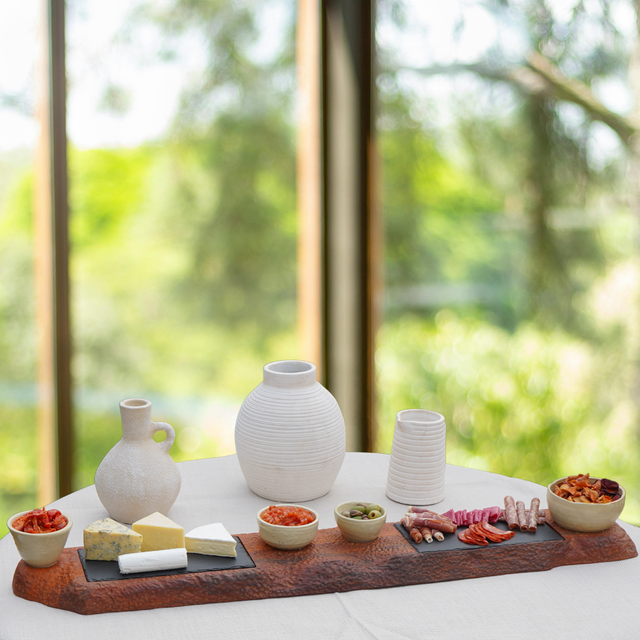 Table with a charcuterie board and ceramic vases in a bright outdoor setting