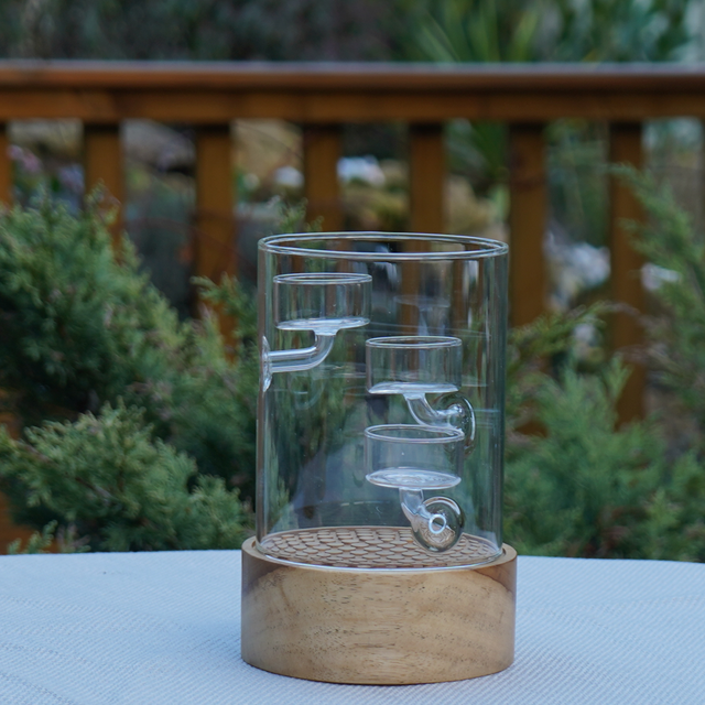 Glass vase with wooden base on a table outdoors