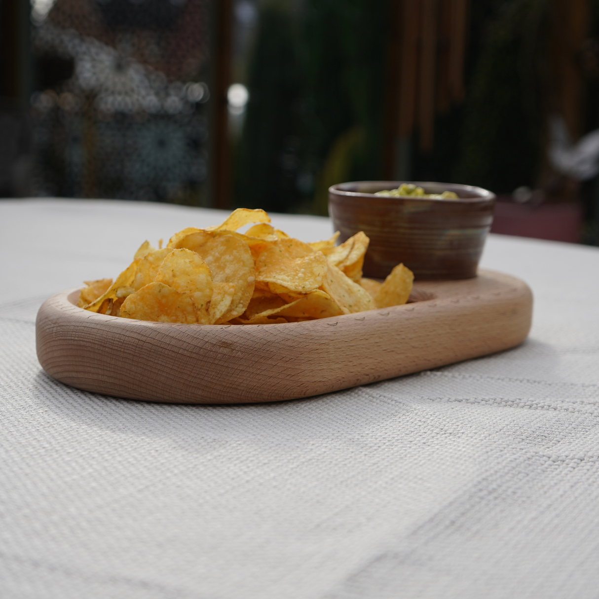 Wooden plate with chips and a small bowl on a textured surface