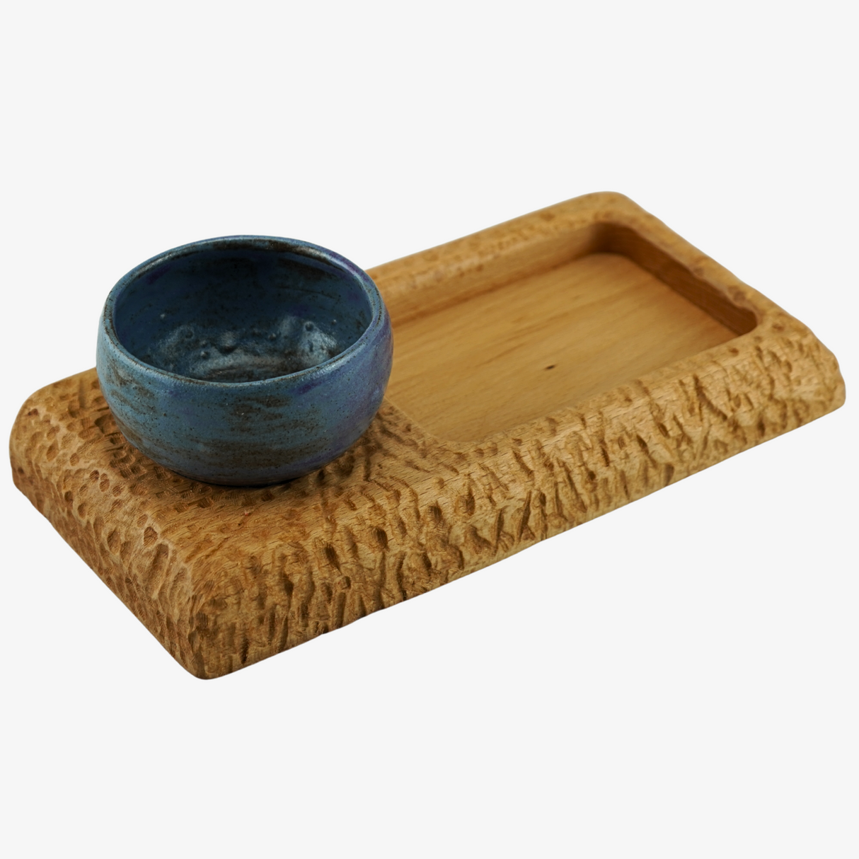Blue ceramic bowl on a textured wooden tray with a white background