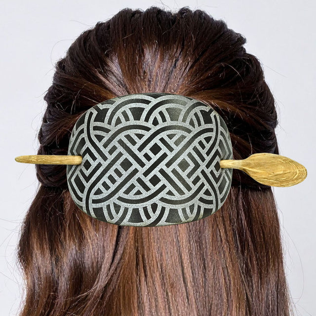 Decorative hairpin with intricate design in a person's hair against a white background