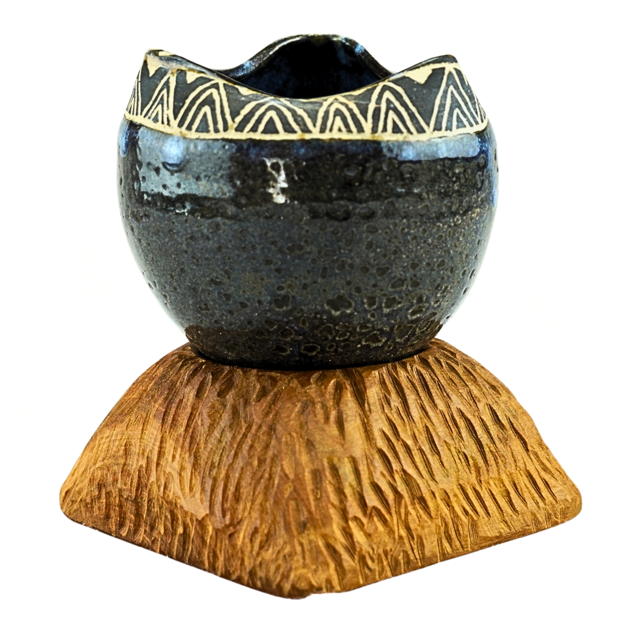 Ceramic bowl with decorative patterns on a wooden base against a white background