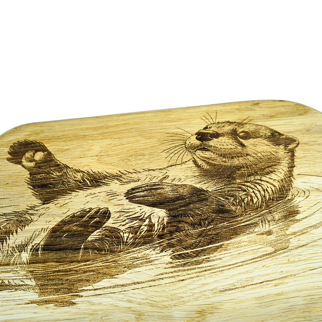 Wooden cutting board with engraved otter design on a white background