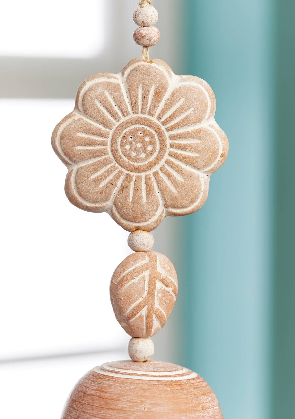 Decorative wooden bead with floral design against a blurred background