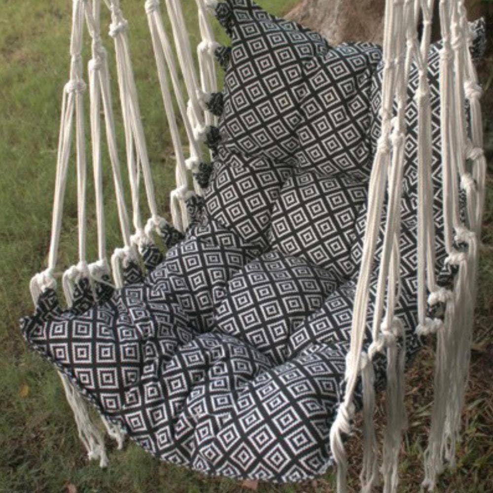 Person sitting in a black and white patterned hammock chair outdoors.