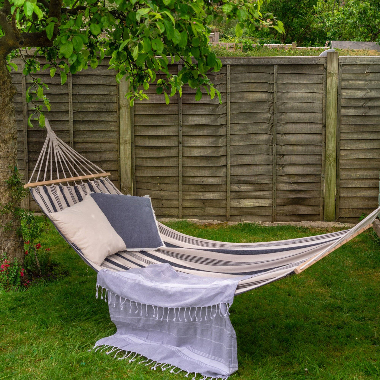 Hammock with striped fabric and pillows in a garden setting