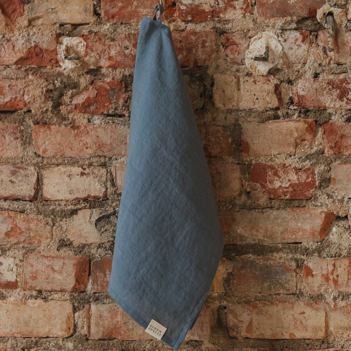 dark grey towel hanging on a brick wall