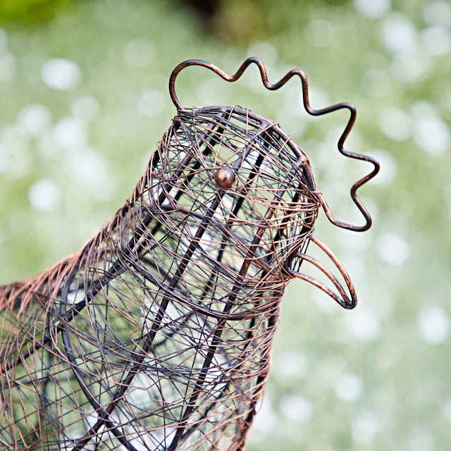 Decorative wire rooster sculpture on a grassy lawn