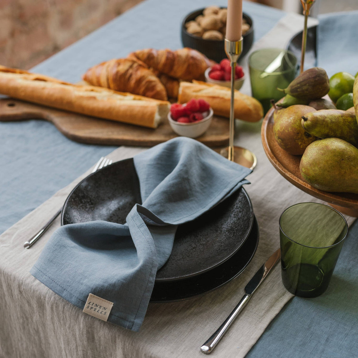 A blue linen napkin folded beside plates and cutlery.