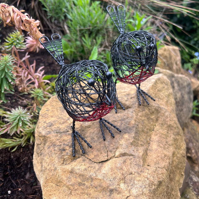 A pair of decorative wire Robbins on a rock with greenery