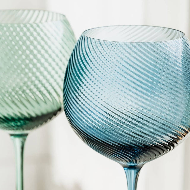 Two blue glass wine glasses with textured design on a white background