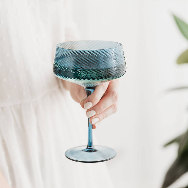 Hand holding a blue glass with a white background