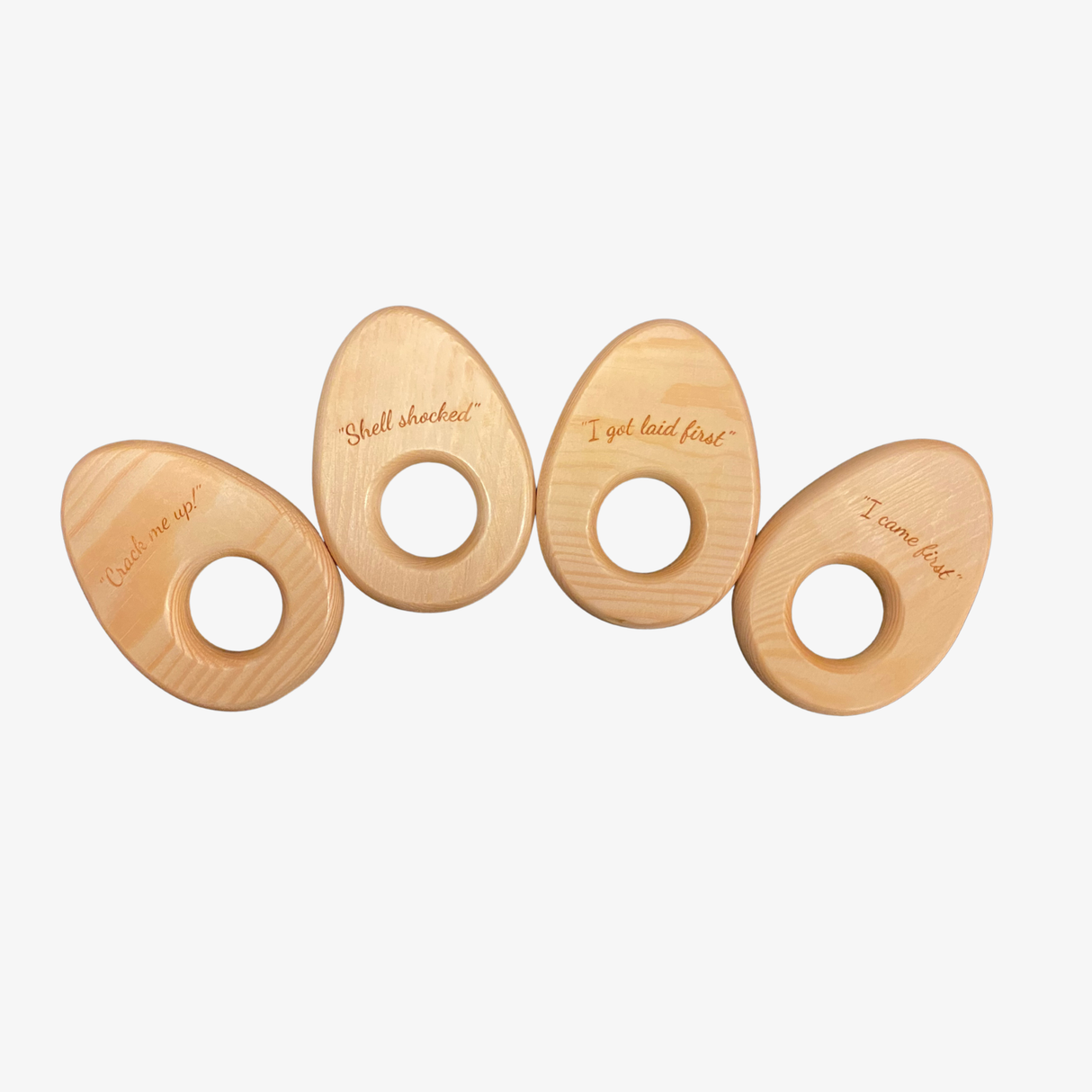 Four wooden egg holder rings with humorous inscriptions on a white background
