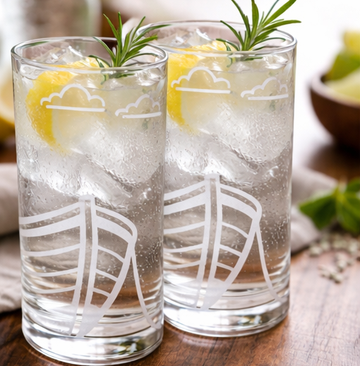two FJAERE Boat Etched Glass Tumblers with lemon and rosemary on a wooden surface.