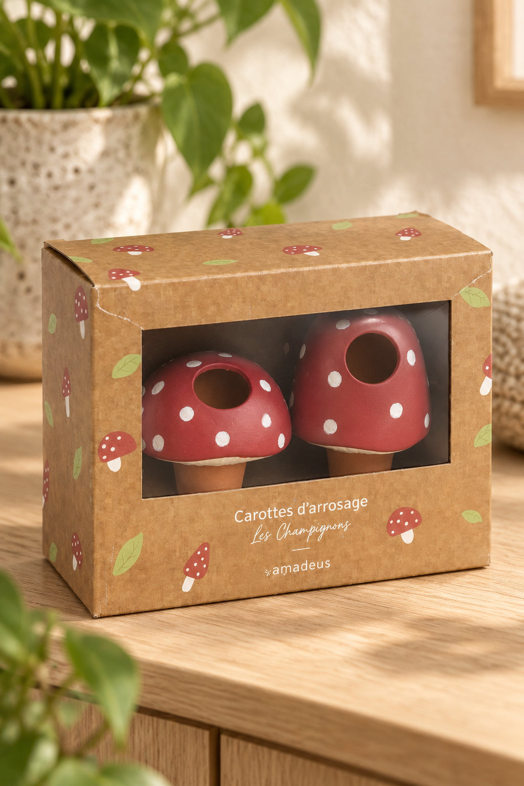 Set of two terracotta plant watering spikes with red mushroom caps, white spots and cream detailing. Includes one rounded and one taller mushroom design, each with an open filling hole and a tapered stem. Suitable for indoor pots and balcony planters. Presented in a windowed box with mushroom and leaf.