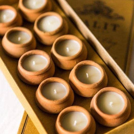 Set of small terracotta candles in a box with a brand name on the lid.