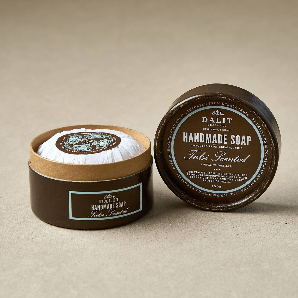 Handmade soap tulsi scented in a brown container with a visible label on a beige background