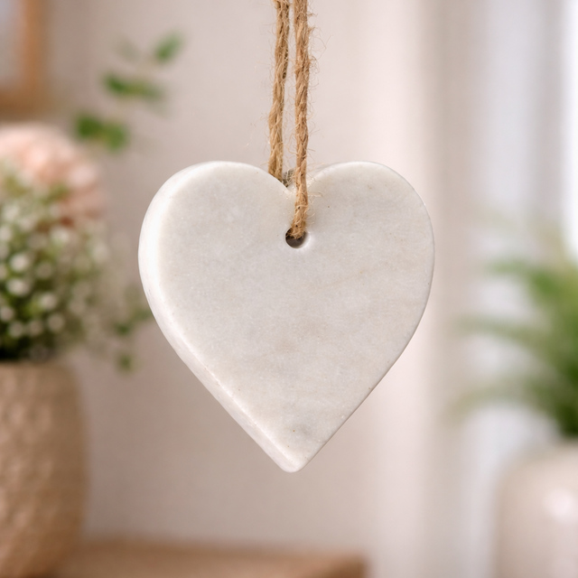 White marble heart-shaped hanging ornament on a rope with a blurred indoor background