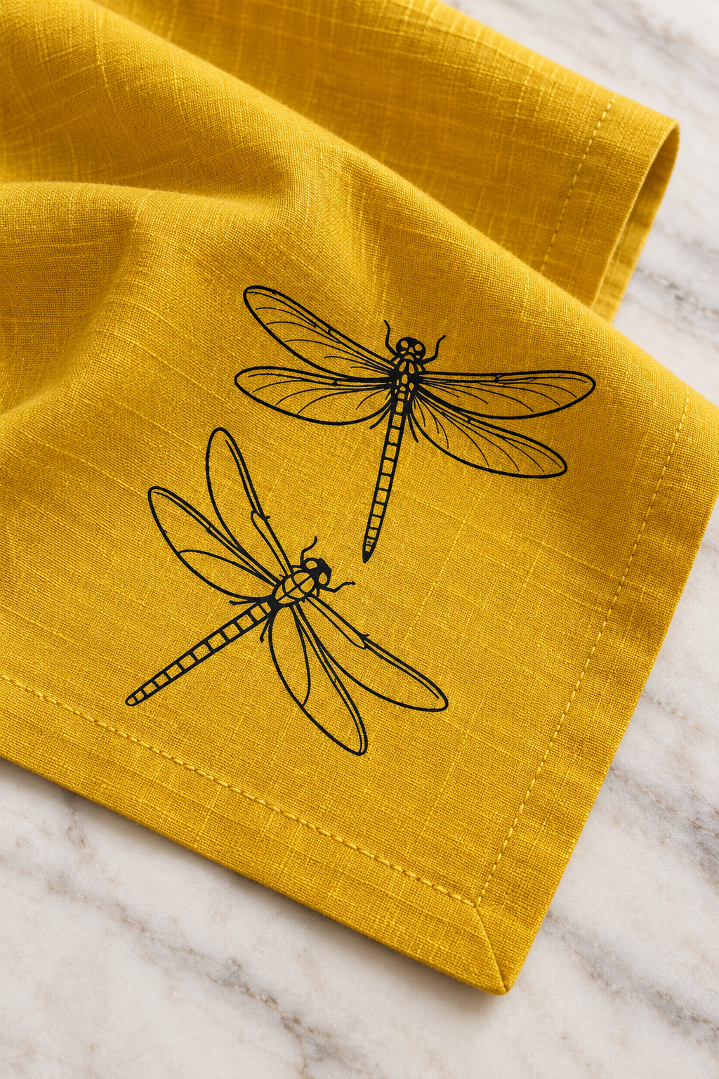 Close-up of two black dragonflies printed on mustard linen, showing the woven texture and matching yellow stitching.