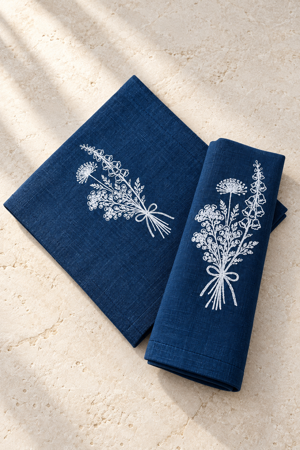 Close-up of a white Florilegium bunch hand screen printed on navy linen, showing the fabric weave and stitched hem.