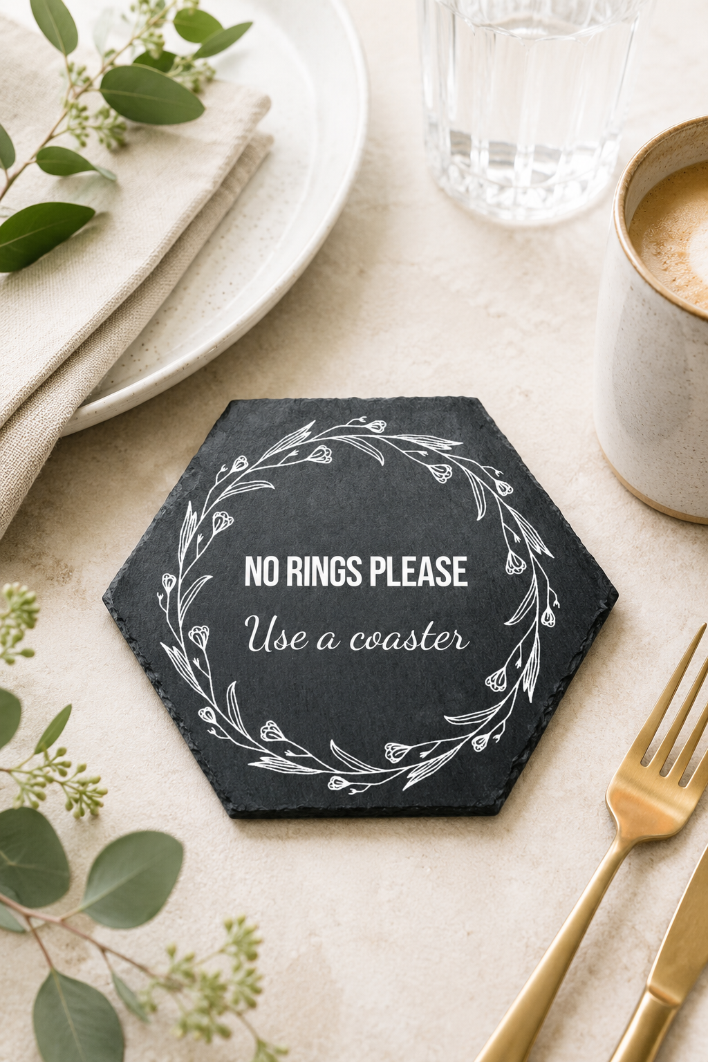 Hexagonal coaster with 'No Rings Please Use a Coaster' text on a table setting with a cup, fork, and greenery.