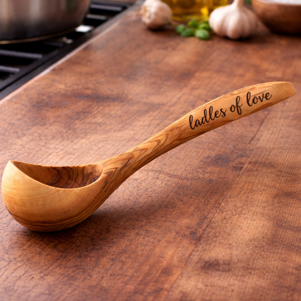 Wooden ladle with 'Ladles of love' engraving on a wooden surface.