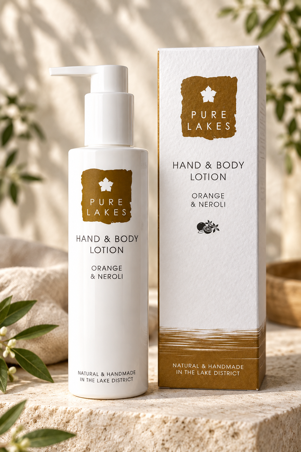 Pure Lakes Hand & Body Lotion in Orange & Neroli scent, shown as a white pump bottle next to its white and gold packaging box on a stone surface with soft botanical background.