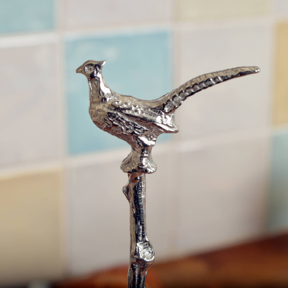 Silver pheasant-shaped object against a blurred background