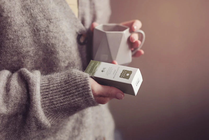Person holding a mug and a box in a warm setting