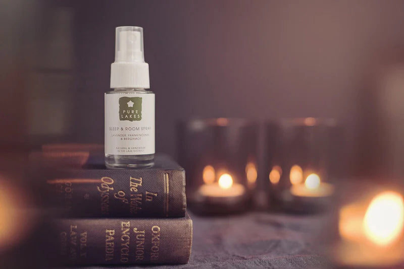 Spray bottle on books with candles in the background