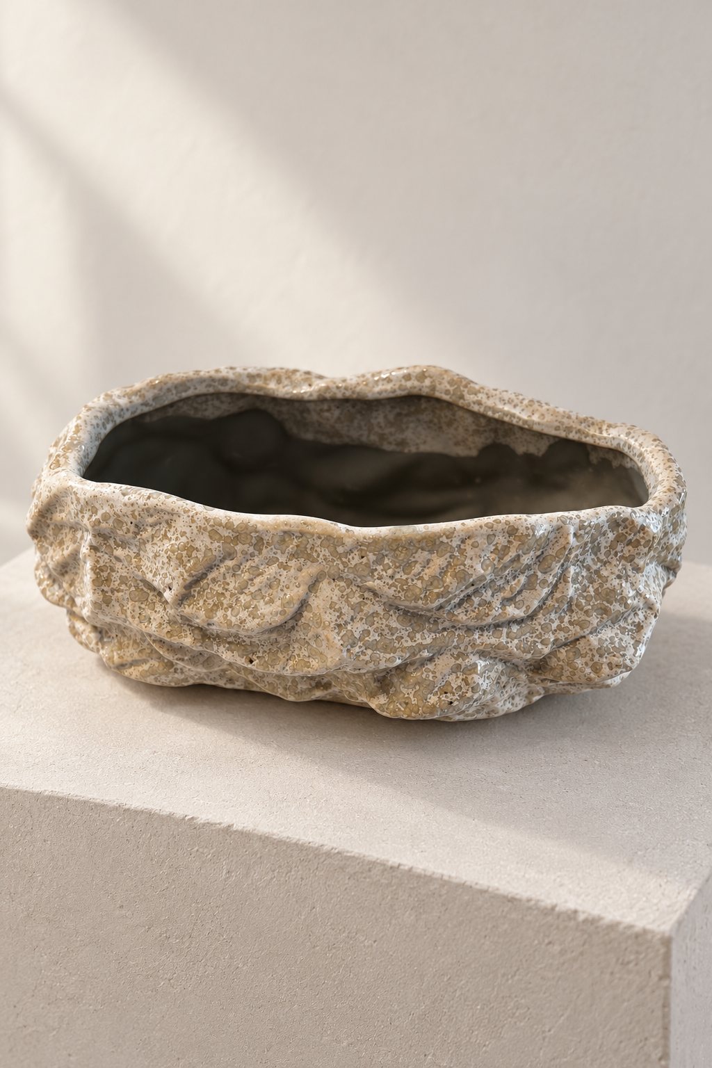 Empty rock effect ceramic plant pot showing its irregular rim and mottled grey and cream texture