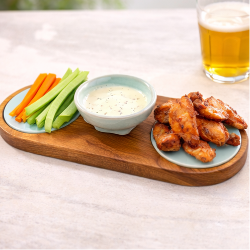 a wooden tray with snacks and dips on a table outdoors.