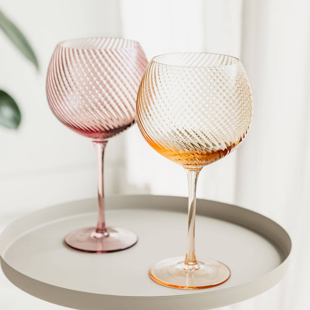 Two textured wine glasses on a white tray with a light background