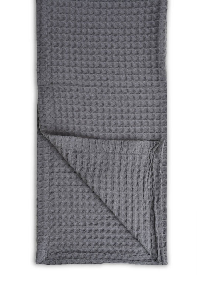 Grey textured blanket folded on a white background
