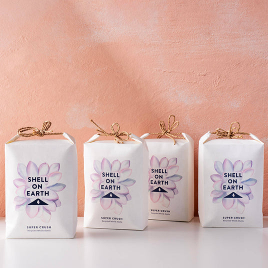 Four 'Shell on Earth' packages with floral designs on a pink background