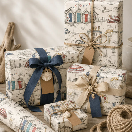 Coastal birthday wrapping paper on gifts tied with navy and natural ribbon, styled with shells and driftwood.