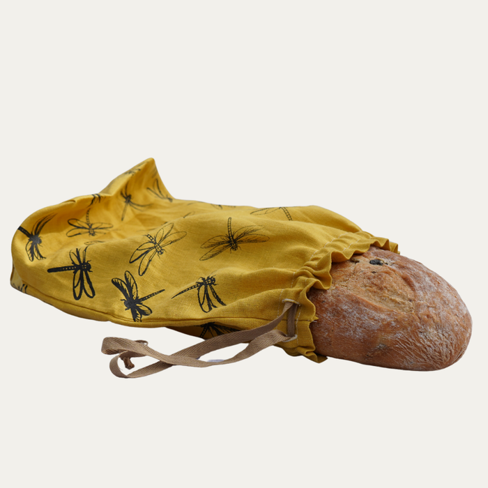 Loaf of bread wrapped in a yellow cloth with black insect patterns on a white background