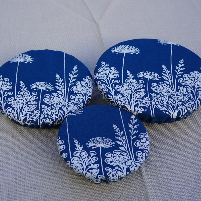Three blue fabric discs with white floral patterns on a grey surface