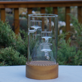 Glass container with a wooden base on a surface outdoors