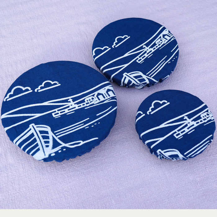 Three blue bottle caps with white airplane and cloud design on a light purple background