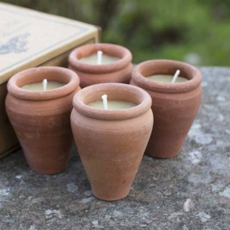 Four terracotta pots with candles on a stone surface