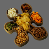 Wooden snack tray with compartments filled with various snacks on a gray background