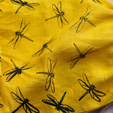 Yellow drawstring bag with black dragonfly patterns next to a loaf of bread on a textured surface