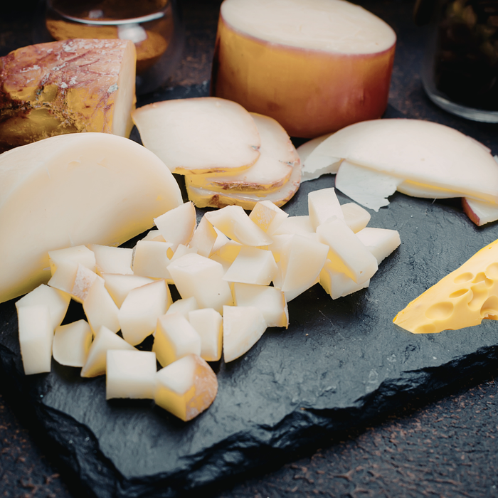 Diced cheese on a dark slate surface with whole apples in the background