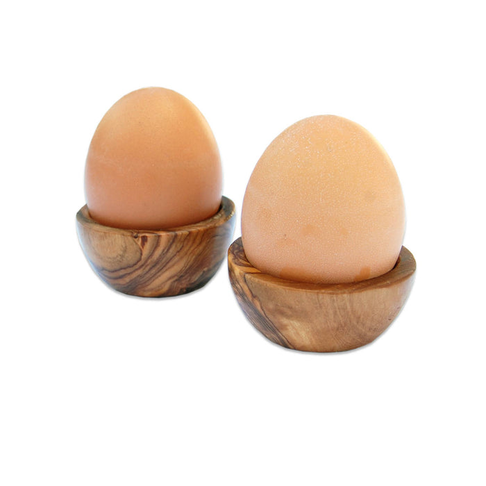 Two brown eggs in wooden holders on a white background