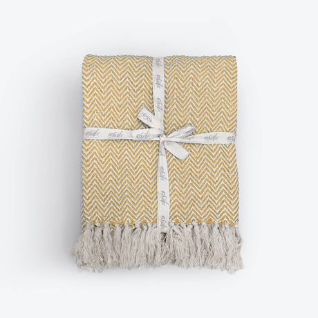 Yellow and white patterned blanket with tassels on a white background