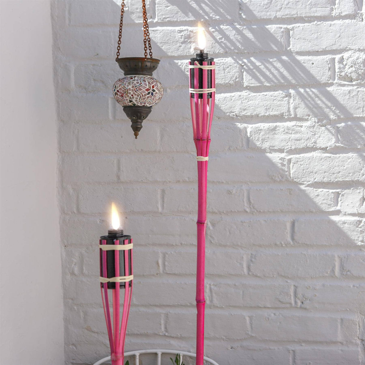 Pink torches with flames against a white brick wall