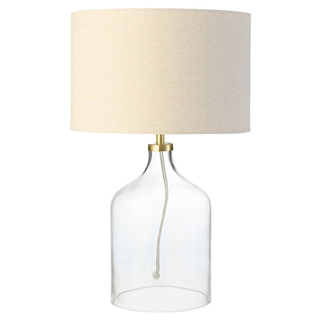 Table lamp with clear glass base and beige fabric shade on a white background