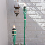 Two green torches with flames against a white brick wall.
