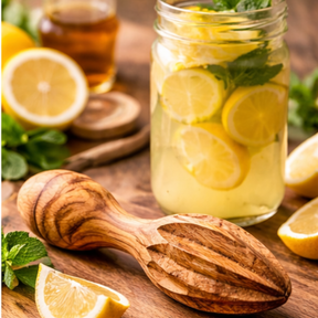Mason jar with lemon slices and mint leaves on a wooden surface with a wooden spoon and lemons.